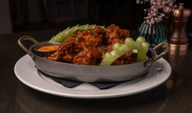 Succulent spicy chicken wings with celery on elegant plate at hotel restaurant.