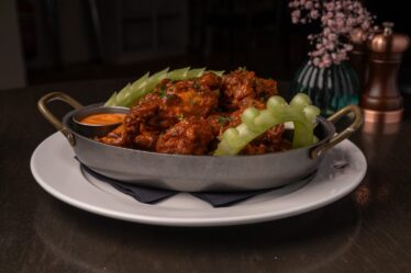 Succulent spicy chicken wings with celery on elegant plate at hotel restaurant.