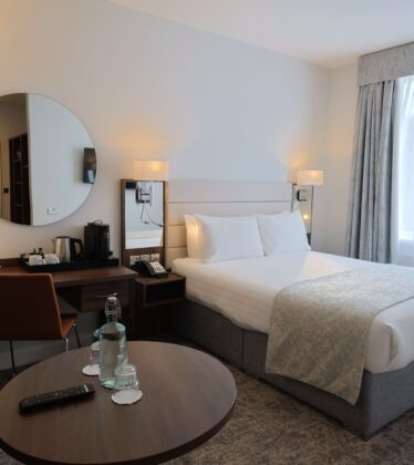 Elegant hotel room with king-size bed, soft lighting, a cosy seating area, and complimentary refreshments; ideal for relaxation.