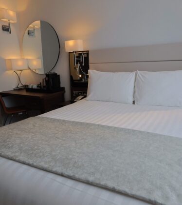 Elegant hotel room with cosy bed, stylish lighting, and a convenient desk for a comfortable stay.