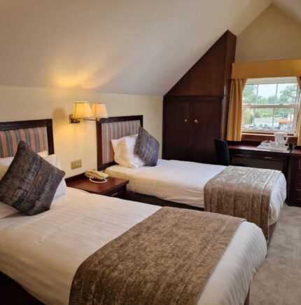 Cosy hotel room with twin beds, plush cushions, warm lighting, and a scenic view; ideal for a relaxing getaway.
